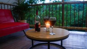 una mesa con dos copas y una botella de vino y una vela en Glamping Salento y Posada Villa Alegría, en Salento