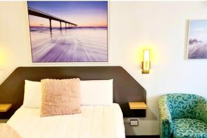 a bedroom with a bed and a picture of a pier at Golden Sands Motor Inn in Forster