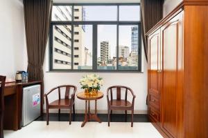 Habitación con mesa, 2 sillas y ventana en HOÀNG HOTEL, en Ho Chi Minh