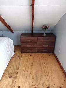 a bedroom with a dresser with a vase of flowers on it at Casa en sector isla teja in Valdivia