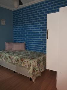 Morada do Sol de Iguaba AP 2 qts في إيغوابا غراندي: غرفة نوم مع سرير بجدار من الطوب الأزرق