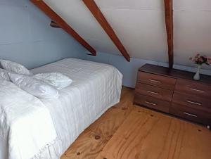 a bedroom with a white bed and a wooden dresser at Casa en sector isla teja in Valdivia