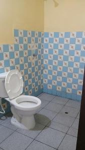 a bathroom with a toilet and a blue tiled wall at Casas Cueva in Tumbes