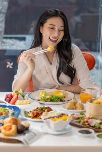 una mujer comiendo comida en una mesa con platos de comida en Four Points by Sheraton Bangkok, Sukhumvit 15, en Bangkok