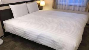 津市にある東横INN津駅西口のホテルルーム内の大きな白いベッド
