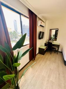 a hotel room with a desk and a large window at Swing & Pillows - Corona Inn Bukit Bintang in Kuala Lumpur