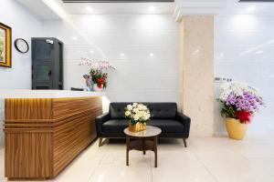 una sala de espera con sofá y mesa con flores en HOÀNG HOTEL, en Ho Chi Minh