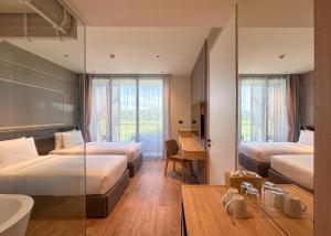 una camera d'albergo con due letti e un bagno di La Green Hotel and Residence a Bang Tao Beach