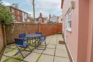 eine Terrasse mit Tisch und Stühlen und einer Backsteinmauer in der Unterkunft Poppy Cottage in Southwold