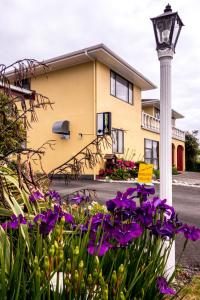 una casa amarilla con flores púrpuras y luz de la calle en Ascot Motor Lodge, en Westport