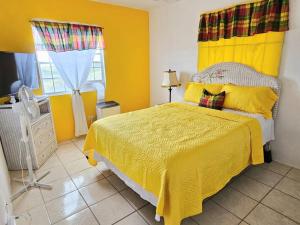 a bedroom with a bed with a yellow bedspread at Veronica's Tropical Oasis in Christiansted