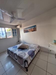 Schlafzimmer mit einem Bett und einem Deckenventilator in der Unterkunft Villa bois rose in Petit-Bourg