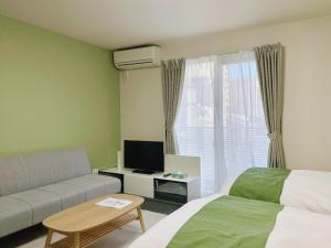 a room with a couch and a bed and a tv at Calm Stay Nijo in Kyoto