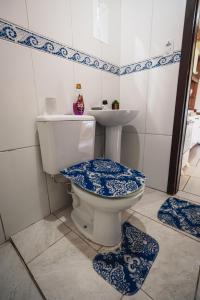 La salle de bains est pourvue de toilettes bleues et blanches et d'un lavabo. dans l'établissement Pousada Salinas Valle, à Tramandaí