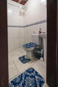 La salle de bains est pourvue de toilettes, d'un lavabo et de carrelage bleu et blanc. dans l'établissement Pousada Salinas Valle, à Tramandaí