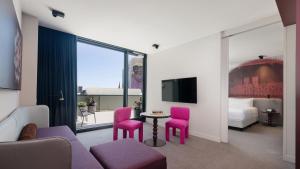 Pokój hotelowy z różowymi krzesłami, stołem i telewizorem w obiekcie Hotel Indigo Sydney Potts Point, an IHG Hotel w mieście Sydney