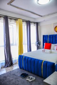 - une chambre dotée d'un grand lit avec des rideaux bleus et jaunes dans l'établissement Heartland Garden Kilimani, à Nairobi