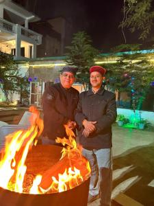 two men standing in front of a fire pit at Shivansh Inn Resort in Rishīkesh