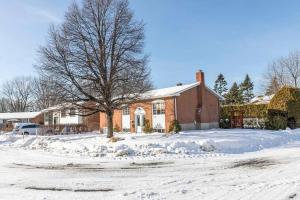 a brick house with a tree in the snow at Fancy 4BDR near DT free parking in Brossard