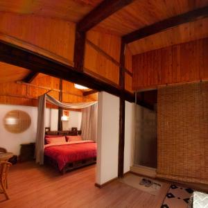 麗江市にあるFull Moon Innの赤いベッドと木製の天井が備わるベッドルーム1室が備わります。