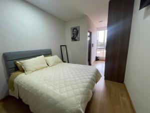 um quarto com uma cama com um edredão branco em Monoambiente full amoblado Cala Cala piso 2 em Cochabamba