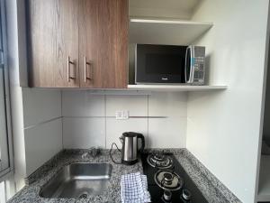 uma pequena cozinha com um lavatório e um micro-ondas em Monoambiente full amoblado Cala Cala piso 2 em Cochabamba