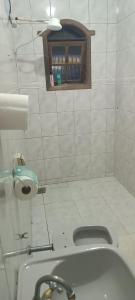 a white tiled bathroom with a sink and a toilet at Hostel Kinu in Belo Horizonte