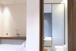 uma casa de banho com uma cama, um WC e um espelho. em Glaze Garden Hotel em Yangzhou