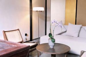 Glaze Garden Hotel في يانغتشو: غرفة معيشة مع مزهرية مع الزهور على طاولة