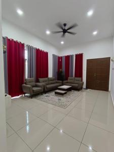 una sala de estar con cortinas rojas y sofás en Homestay Gua Musang, en Gua Musang