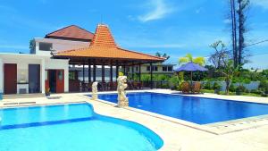 a swimming pool with a gazebo next to a house at Puri Lovina in Lovina