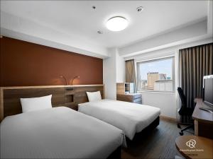 a hotel room with two beds and a window at Daiwa Roynet Hotel Sendai in Sendai