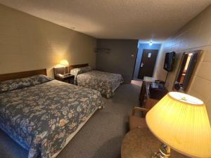 a hotel room with two beds and a lamp at Capri Motor Inn in Smithers