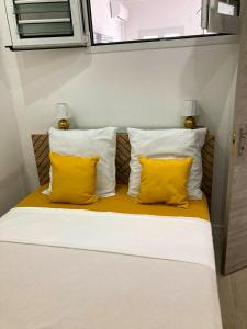 a bed with two yellow pillows and two lamps at Savanna Sky in Fort-de-France