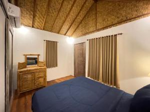een slaapkamer met een blauw bed en een televisie bij Rumah Tiga Gili #Panggung in Gili Air