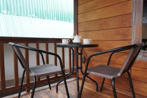 2 stoelen en een tafel in een kamer met een raam bij Rumah Tiga Gili #Panggung in Gili Air