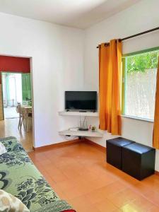 Il comprend un salon doté d'une télévision et d'une fenêtre. dans l'établissement Casa Completa e Independente em Cabo Frio - RFV106, à Cabo Frio