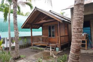 een houten huis met een veranda en palmbomen bij Rumah Tiga Gili #Panggung in Gili Air