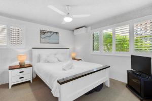 a white bedroom with a bed and a flat screen tv at Riverview Two Apartments in Mooloolaba