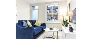 City Elegance: Spacious 2BR for Urban Comfort في تويكنهام: غرفة معيشة مع أريكة زرقاء وطاولة