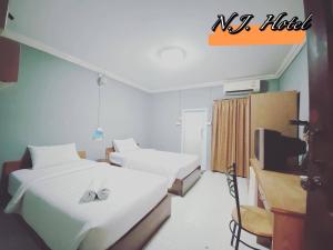 ein Hotelzimmer mit 2 Betten und einem TV in der Unterkunft โรงแรมเอ็น.เจ. ธาตุพนม 