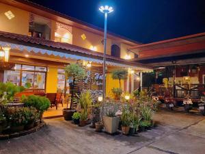 a restaurant with potted plants in front of it at night at โรงแรมเอ็น.เจ. ธาตุพนม 