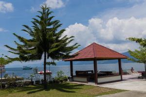 a gazebo with a palm tree next to the water at Gokhon Guest House in Tuk Tuk