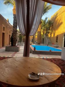 a table in front of a pool with a curtain at Riad Sahara Activity in Mhamid