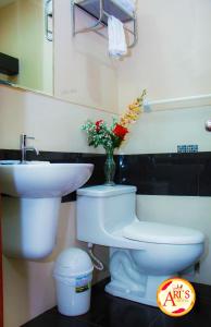 baño con aseo, lavabo y jarrón de flores en ALLISON HOTEL, en Iquitos