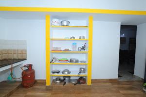 SJ Villa في بونديتْشيري: رف أصفر في غرفة مع أطباق
