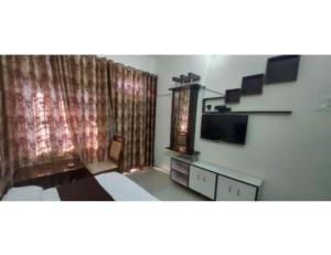 RudraprayāgにあるHotel Govind, Rudrapryagのベッド、テレビ、カーテンが備わる客室です。