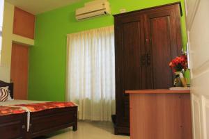 1 dormitorio con paredes verdes, 1 cama y armario en Oshin Home Stay, en Kochi
