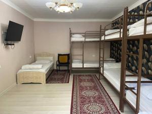 a room with three bunk beds and a television at Sunny Guest House in Osh
