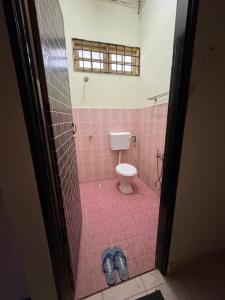 baño con aseo y suelo de baldosa rosa en Syurgaku Homestay Tanah Merah, en Tanah Merah